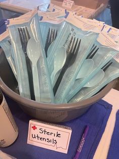 a bowl full of plastic utensils sitting on top of a blue table cloth