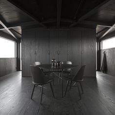 a dining room table surrounded by chairs in front of wooden paneled walls and windows