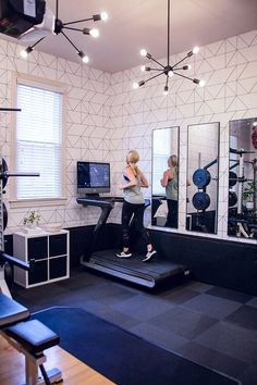 a woman is running on a treadmill in a room with mirrors and other equipment