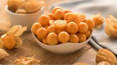 a white bowl filled with oranges on top of a table next to other food items