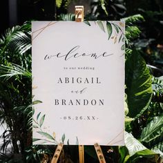 a welcome sign on a easel in front of some plants