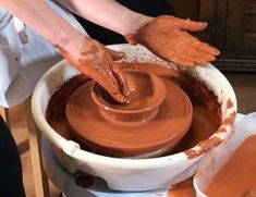 a person is making clay on a potter's wheel with their hands in the bowl