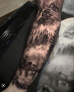 a man's arm with an image of mountains and trees on it