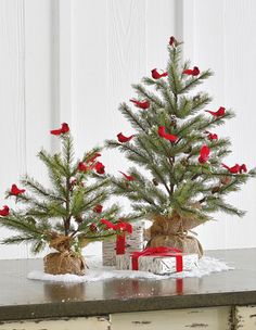 two small christmas trees sitting on top of a table next to boxes with presents under them