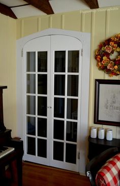 a living room with a piano in the corner and a wreath on the wall above it