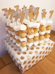 there is a cake with gold and silver decorations on the top, sitting on a white box