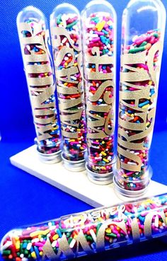 three clear vases filled with colorful sprinkles and the word happy on them