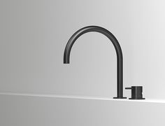 a black faucet sitting on top of a bath tub next to a white wall