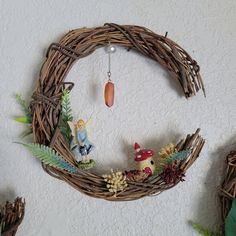 a wreath with figurines hanging from it's sides and plants around it