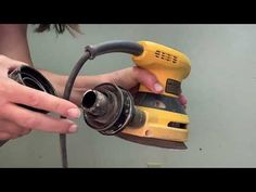 a person holding a yellow and black electric sander