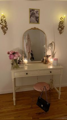 a dressing table with a mirror, stool and flowers in front of it on top of a hard wood floor