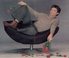 a man sitting in a chair with roses around him