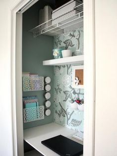 a laptop computer sitting on top of a white desk next to a wallpapered wall