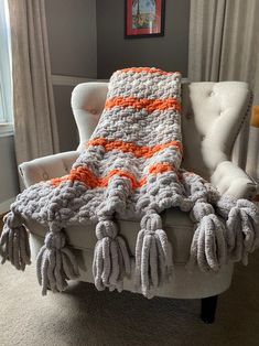 an orange and white crocheted blanket sitting on top of a chair