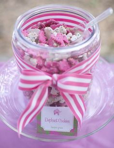 a jar filled with pink and white candies sitting on top of a glass plate