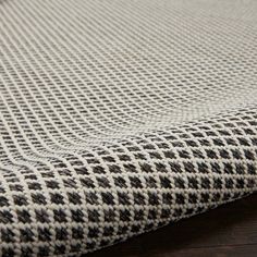 a close up view of a rug on a wooden floor with black and white checkered fabric