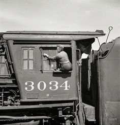 an old black and white photo of a man in the caboose of a train