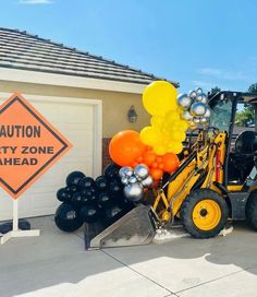 a tractor with balloons attached to it parked in front of a construction zone warning sign