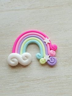 a close up of a toy rainbow with stars and clouds on the top, sitting on a wooden surface