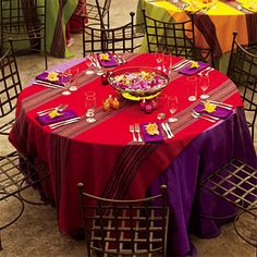 a red table topped with a plate of food next to other tables covered in purple and yellow cloths