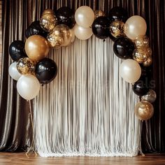 black, gold and white balloons are arranged in the shape of a heart