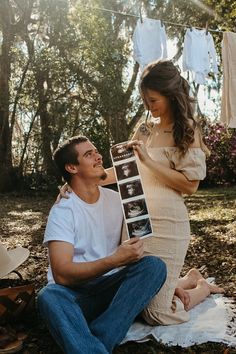 a pregnant woman sitting on the ground next to a man holding an old film camera