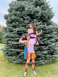 a man and woman are standing in front of a large tree with one holding the other