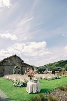 an outdoor ceremony set up in front of a barn