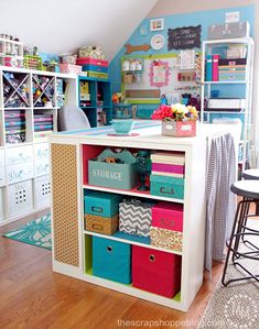 an organized craft room with lots of storage and colorful bins on the bottom shelf