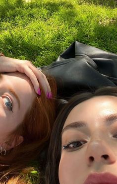 two women laying in the grass with their hands on each other's heads and one has her eyes closed