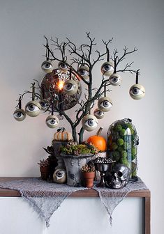 a halloween tree decorated with fake eyes and decorations on top of a mantle in front of a white wall