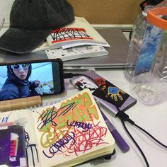 a cell phone sitting on top of a table next to a book and some pens