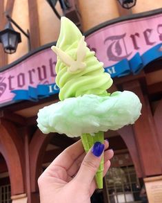 a hand holding an ice cream cone in front of a building