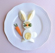 a white plate topped with cut up eggs and an egg shaped like a bunny next to a carrot