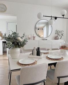 a dining room table with plates and place settings on it, in front of a large round mirror