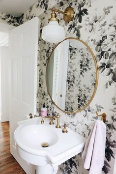 a white sink sitting under a bathroom mirror next to a wall mounted faucet