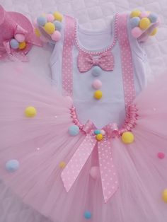 a pink tutu with polka dots and bows on the top, is laying on a bed