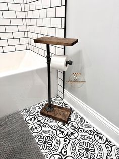 a bathroom with a black and white tile floor next to a toilet paper roll holder