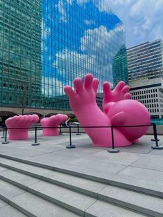 large pink sculptures in the shape of hands on top of some steps next to a building