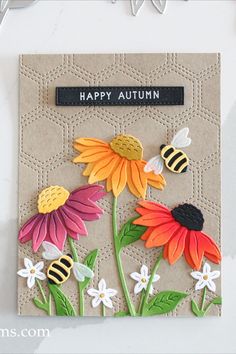 a handmade card with flowers and bees on it, says happy autumn in black lettering