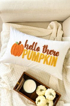 a pillow that says hello there pumpkin next to some candles