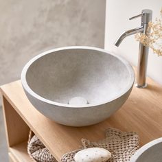 a bowl shaped sink sitting on top of a wooden counter next to a faucet