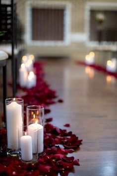 candles are lined up on the floor with rose petals