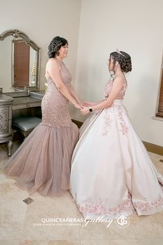 two women in dresses standing next to each other near a desk with a mirror on it