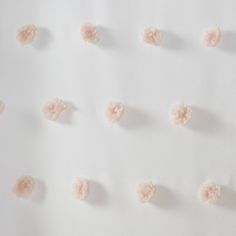 the wall is made up of small pink pom - poms on white paper