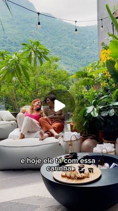 two women sitting on bean bag chairs in an outdoor area with trees and mountains in the background