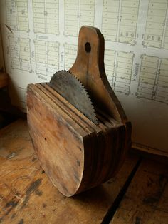 an old wooden tool holder sitting on top of a wooden table next to a wall