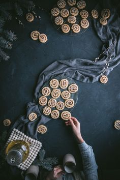 a person holding a plate with cookies on it next to a table full of cookies