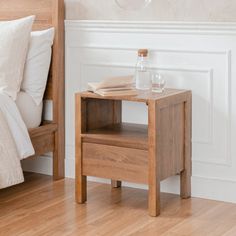 a small wooden table with a book on it next to a bed and nightstand in a bedroom