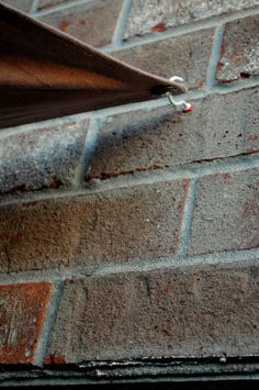 a skateboard resting on the side of a brick wall with nails stuck to it